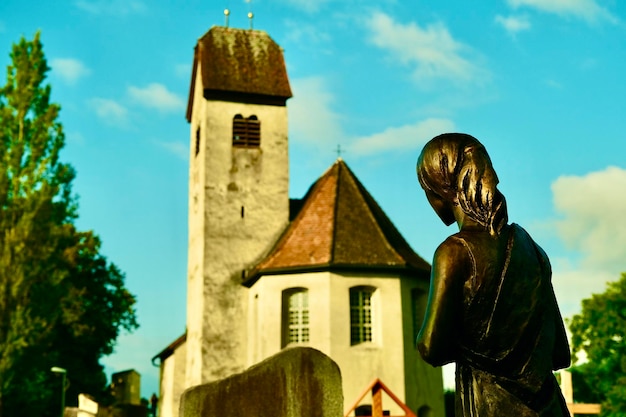 Posąg anioła patrzącego w stronę starego kościoła