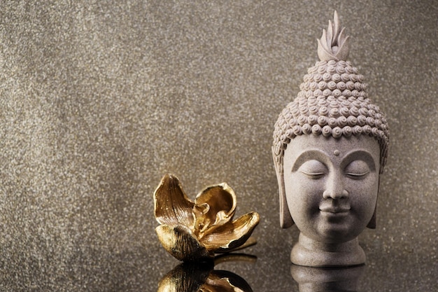 Posąg głowy Buddy i złoty kwiat orchidei. Tło medytacji Zen