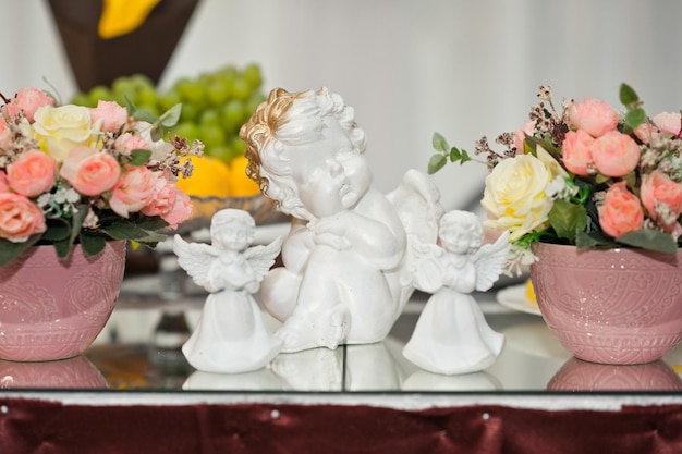 Posąg małego białego aniołka na stole wśród kwiatów 1856