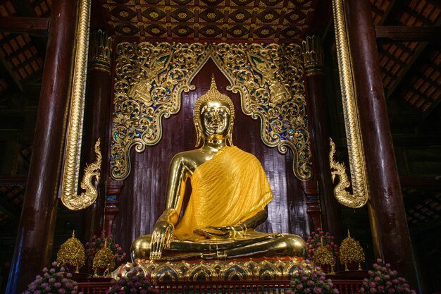 Posąg złotego Buddy siedzi w świątyni.
