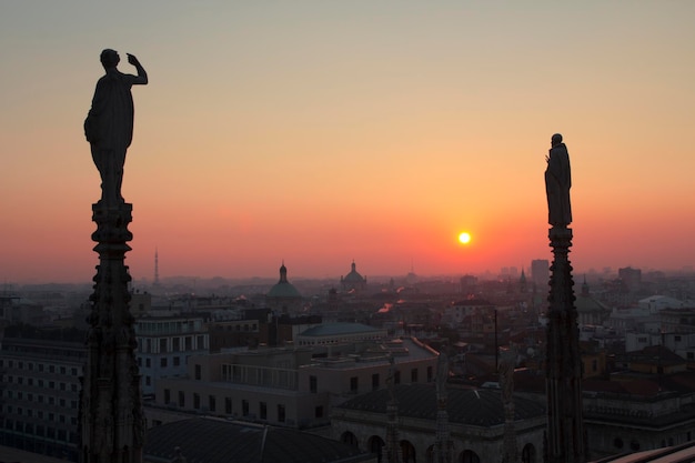 Posągi i elementy dekoracyjne na dachu Duomo. Wieczór Mediolan, widok na miasto z tarasu katedry Duomo.