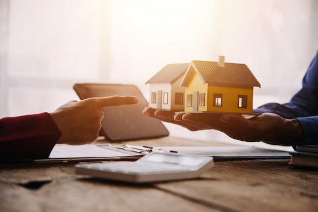 Pośrednik w obrocie nieruchomościami przedstawiający i konsultujący się z klientem w procesie podejmowania decyzji podpisanie umowy ubezpieczenia umowa kupna-sprzedaży model domu dotyczący oferty kredytu hipotecznego i ubezpieczenia domu