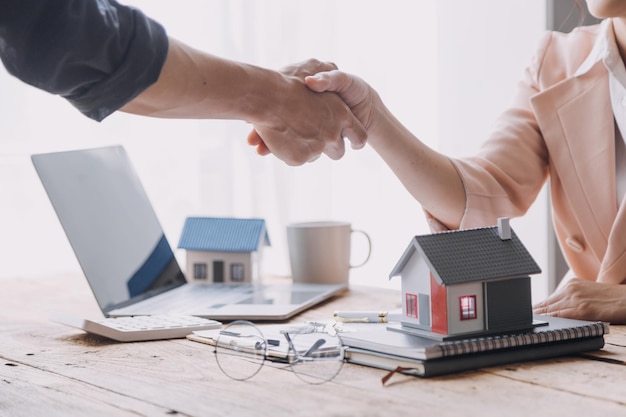 Pośrednik w obrocie nieruchomościami przedstawiający i konsultujący się z klientem w procesie podejmowania decyzji podpisanie umowy ubezpieczenia umowa kupna-sprzedaży model domu dotyczący oferty kredytu hipotecznego i ubezpieczenia domu