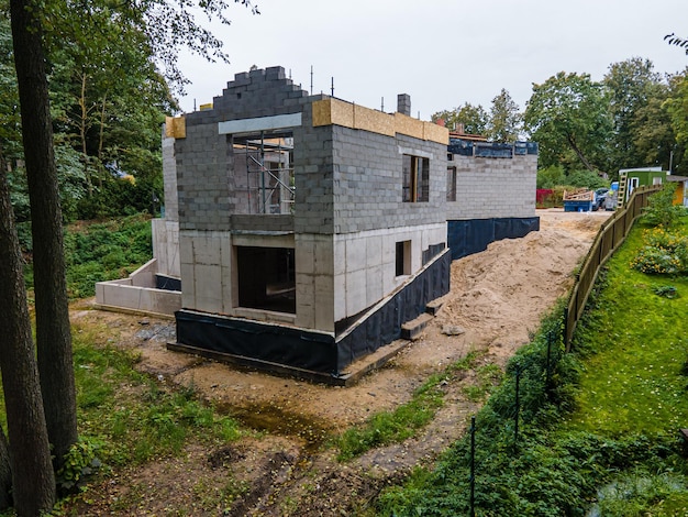 Postęp na budowie domu na przedmieściach z odsłoniętymi ścianami z bloków glinianych i drewnianymi belkami dachu