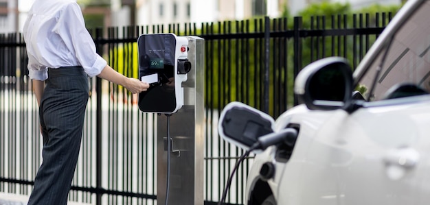 Postępowa kobieta płaci za punkt ładowania do zasilania pojazdu elektrycznego