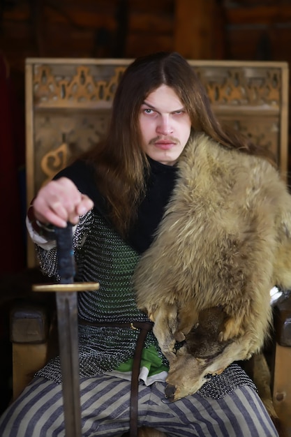 Zdjęcie potężny bohater z długimi włosami w zbroi kolczugowej w starożytnej sali. średniowieczny wojownik w komnatach rycerza.