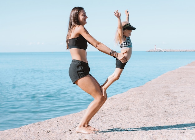 Potomstwa Dostosowywali Kobiety Mamy Z Małą śliczną Dziewczyną ćwiczy Wpólnie Na Plaży