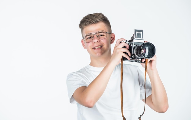 Potrzebujesz bliższego spojrzenia koncepcja fotografii podróżniczej chłopiec w swobodnym ubraniu z aparatem fotograficznym w stylu retro fotografujący fotograf studencki na białym tle technologia aparatu cyfrowego młody nastolatek reporter