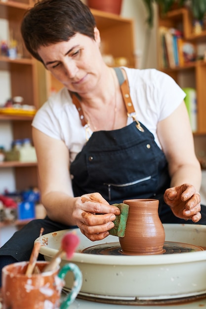 Potter kobieta pracuje na kole z wyrobem glinianym.