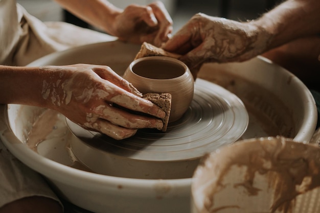 Zdjęcie potter uczy nastolatkę pracującą z kołem ceramicznym z góry z bliska