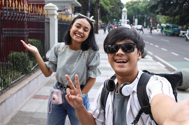 POV szczęśliwej młodej azjatyckiej pary robiącej sobie selfie uśmiechającej się do kamery podczas podróży po mieście
