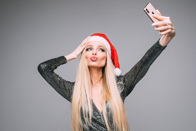 Powabna dziewczyna w Santa kapeluszu i sukni bierze selfie