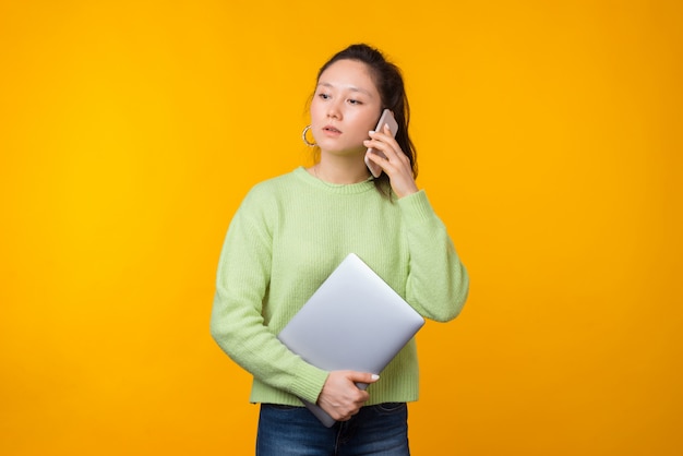 Poważna kobieta rozmawia przez telefon, trzymając laptopa