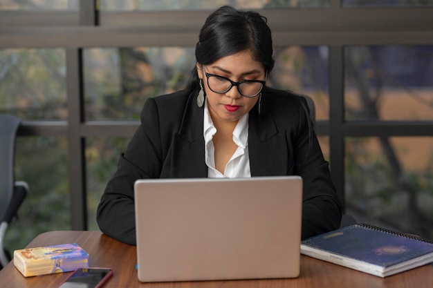 Zdjęcie poważna kobieta w okularach pracująca na laptopie w biurze