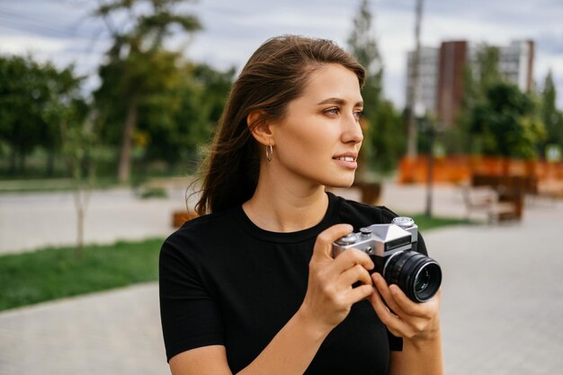 Poważna młoda kobieta chce zrobić zdjęcie trzymając aparat vintage