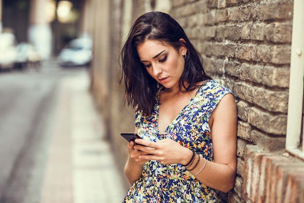 Poważna młoda kobieta używa jej mądrze telefon outdoors.