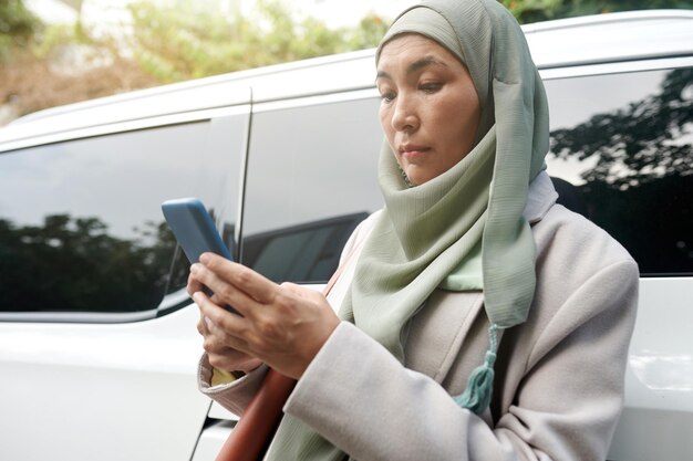 Poważna muzułmańska bizneswoman czyta wiadomości tekstowe od kolegów na smartfonie