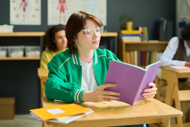 Poważna nastoletnia studentka przeglądająca swoje notatki w zeszycie