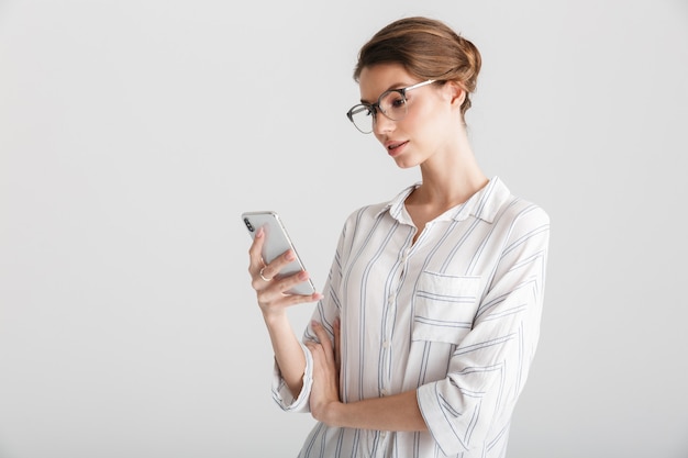 poważna piękna kobieta w okularach, pisząca na telefonie komórkowym na białym tle na białym tle