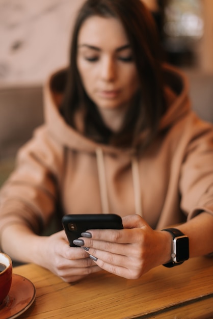 Poważna skoncentrowana młoda kobieta czytająca wiadomość tekstową na telefonie komórkowym w restauracji