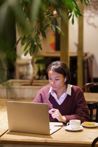 Poważnie Zajęta Afro Pisarka Lub Dziennikarka Pracuje W Kawiarni, Korzystając Z Laptopa I Połączenia Internetowego Wi-fi