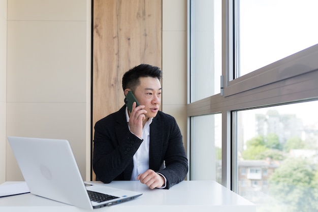 poważny azjatycki biznesmen używa telefonu komórkowego do komunikacji