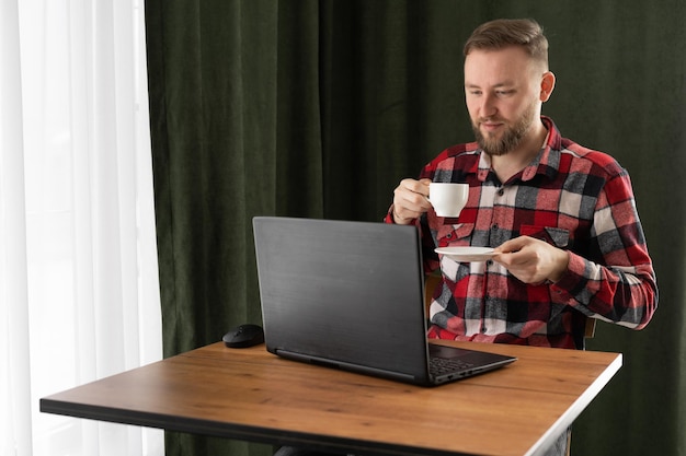 Zdjęcie poważny biały biznesmen pracujący na laptopie w biurze domowym młody europejski student lub nauczyciel zdalny korzystający z komputera uczenie się na odległość uczenie się wirtualne oglądanie webinarów edukacyjnych online