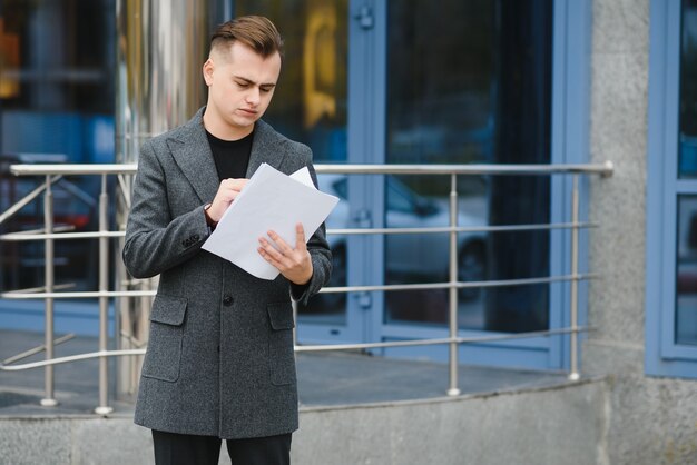 Zdjęcie poważny biznesmen czytanie dokumentów na ulicy