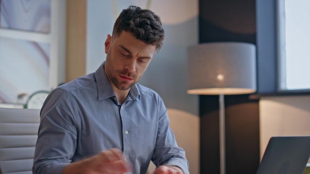 Poważny biznesmen pracujący w biurze piszący na laptopie rano.