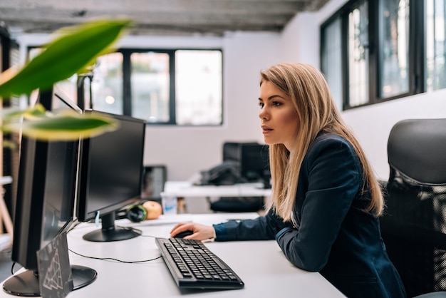 Poważny blondynka bizneswoman pracuje na komputerze.