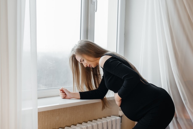 Poważny Ból U Kobiety W Ciąży Stojącej W Pobliżu Okna. Ciąża