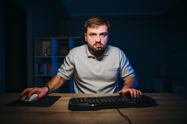 Poważny brodaty freelancer pracuje w domu na komputerze w nocy