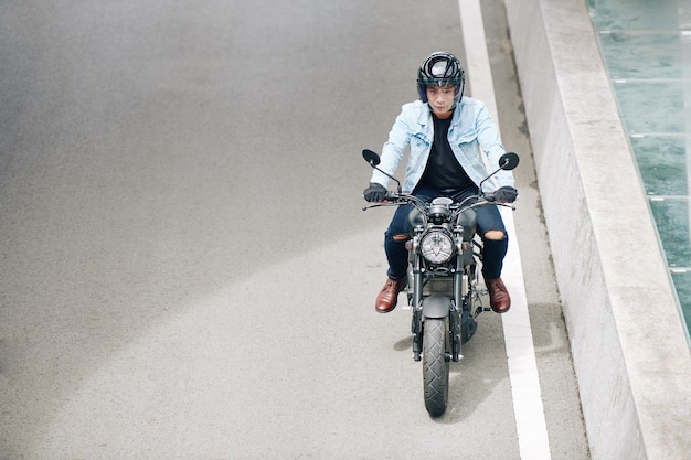 Poważny motocyklista jadący szybko autostradą, dobrze się bawi jadąc po pustej drodze