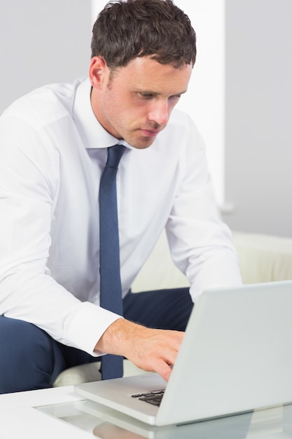 Poważny przystojny biznesmen pracuje przy laptopem