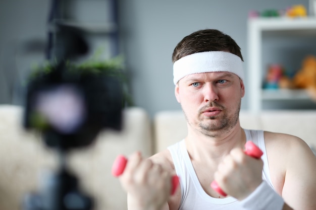 Poważny vlogger robi ćwiczeniom z hantlami