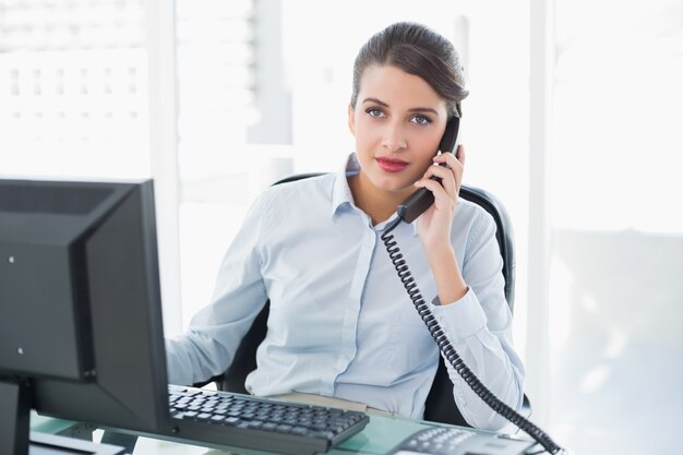 Poważny z klasą brown z włosami bizneswoman odpowiada telefon