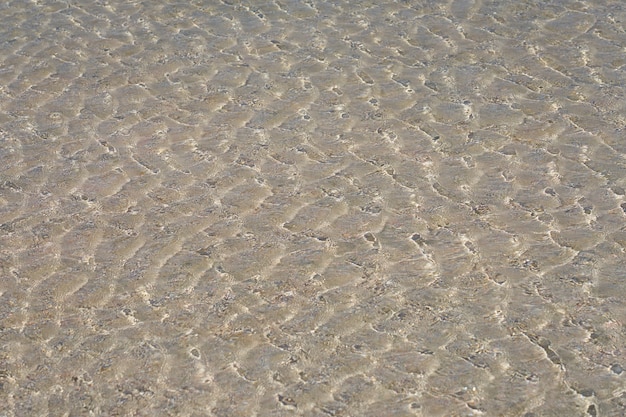 Powierzchnia czystej wody na tropikalnej, piaszczystej plaży w Grecji na Krecie.