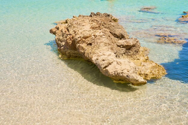 Powierzchnia czystej wody na tropikalnej, piaszczystej plaży z kamieniami w Grecji na Krecie.