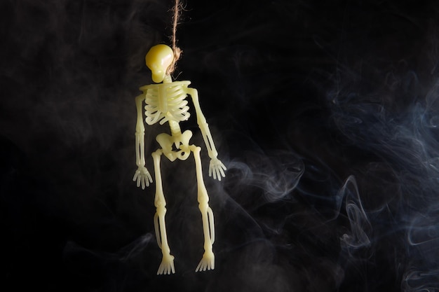Powieszony szkielet na czarnym tle w dymie