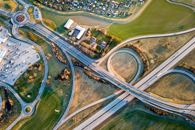 Powietrzny Odgórny Widok Nowożytnego Autostrady Drogi Skrzyżowanie, Domów Dachy Na Wiosny Zieleni Pola Tle. Fotografia Dronów.