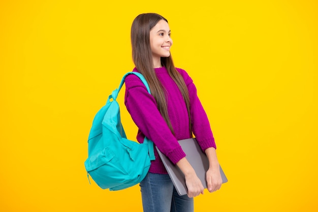 Powrót do szkoły Nastoletnia uczennica trzyma notebook laptopa Dzieci w wieku szkolnym na izolowanym żółtym tle studyjnym