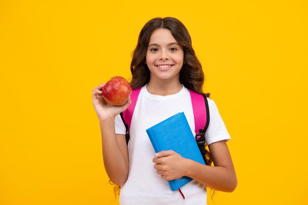 Powrót do szkoły Nastoletnia uczennica z torbą trzyma jabłko i książkę gotowa do nauki Uczennica