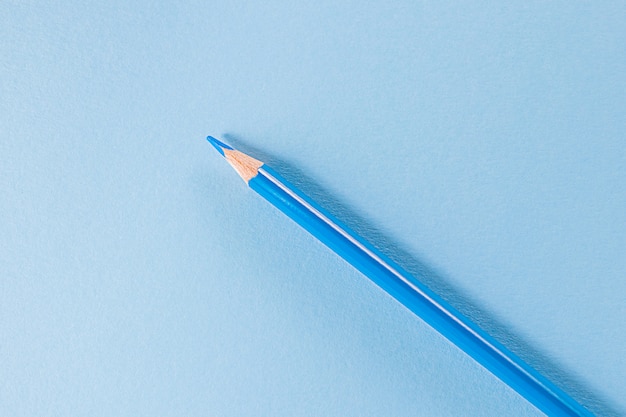 Powrót do szkoły. Niebieski ołówek stoi na niebieskim polu. Obraz monochromatyczny. Kreatywna koncepcja kreatywności dzieci, rysunek.