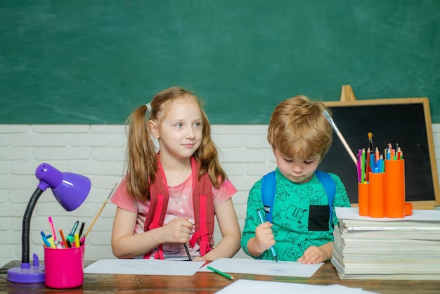 Powrót do szkoły Szkoła dla dzieci Szczęśliwe słodkie pracowite dziecko siedzi przy biurku w pomieszczeniu Proces edukacyjny