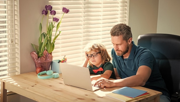 Powrót do szkoły zajęty ojciec i syn w okularach korzystają z komputera w domu rodzinny blog