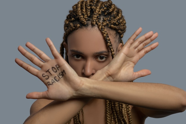 Powstrzymaj rasizm. Młoda kobieta African American przekraczania palm z napisem stop rasizm