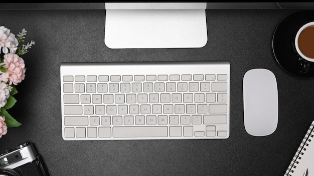 Powyżej widok notebooka z bezprzewodową klawiaturą i myszą i filiżanką kawy na czarnej skórze