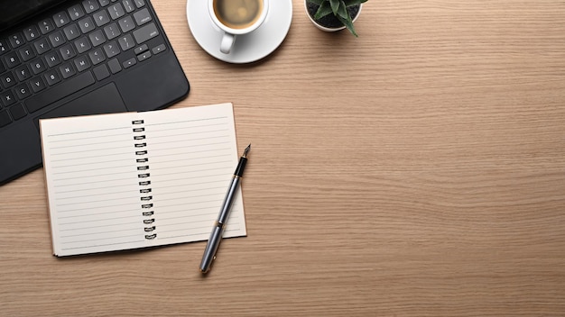 Powyżej widok pusty notatnik długopis filiżanka kawy i laptop na drewnianym stole