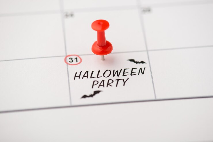 Zdjęcie powyżej zdjęcie daty etykiety 31 października z napisem halloween party dwa nietoperze i czerwoną szpilką na białym tle na tle kalendarza