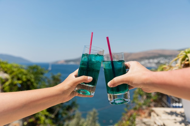 Pozdrawiam Para opiekania z tropikalnymi schłodzonymi niebieskimi napojami z lodem w gorący słoneczny dzień Letnie napoje bezalkoholowe